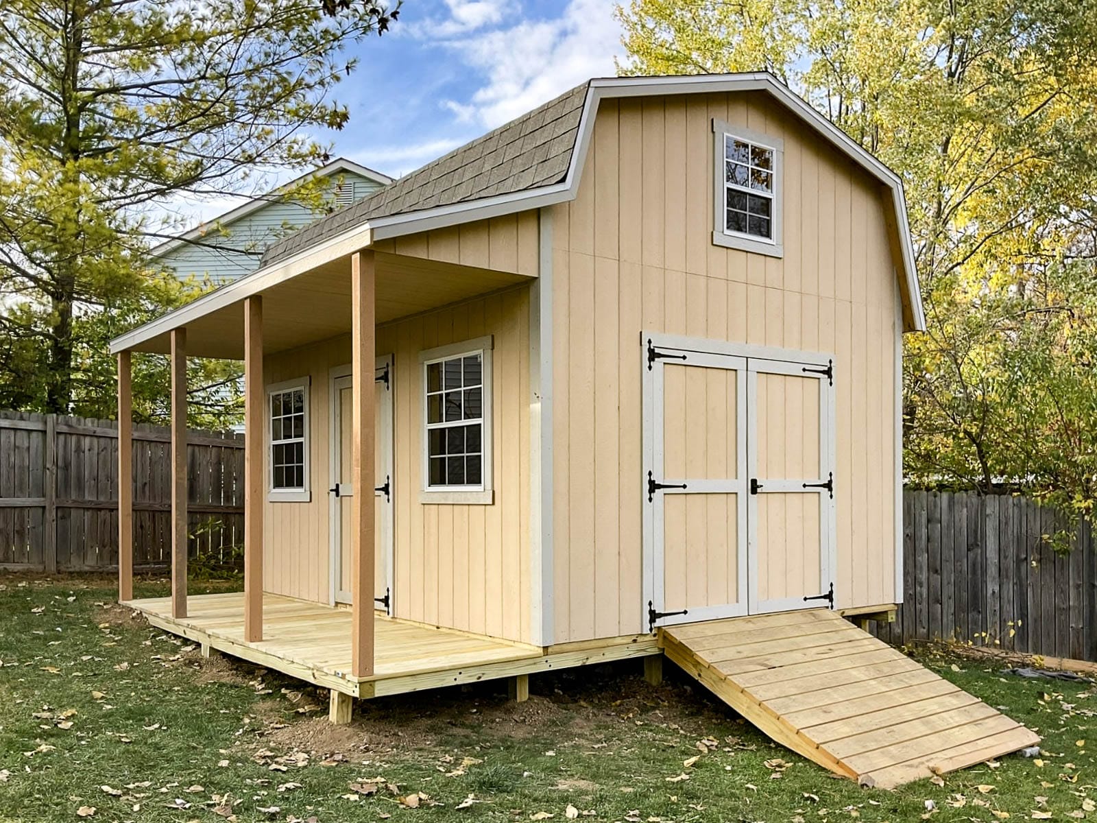 Peach barn-style retreat shed with double doors, windows, and a covered porch.